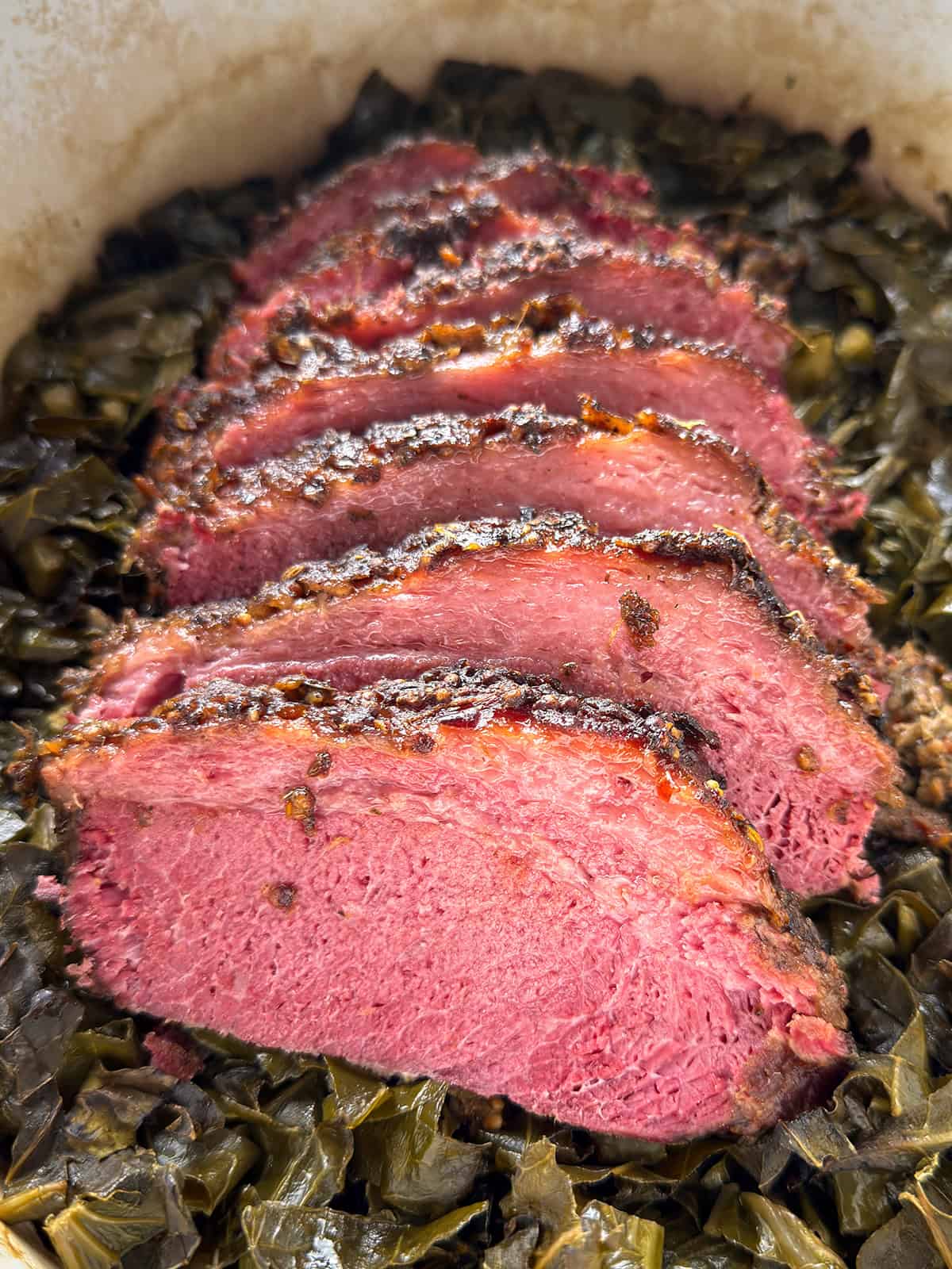 Southern style corned beef with crispy top served over collard greens in a Dutch oven