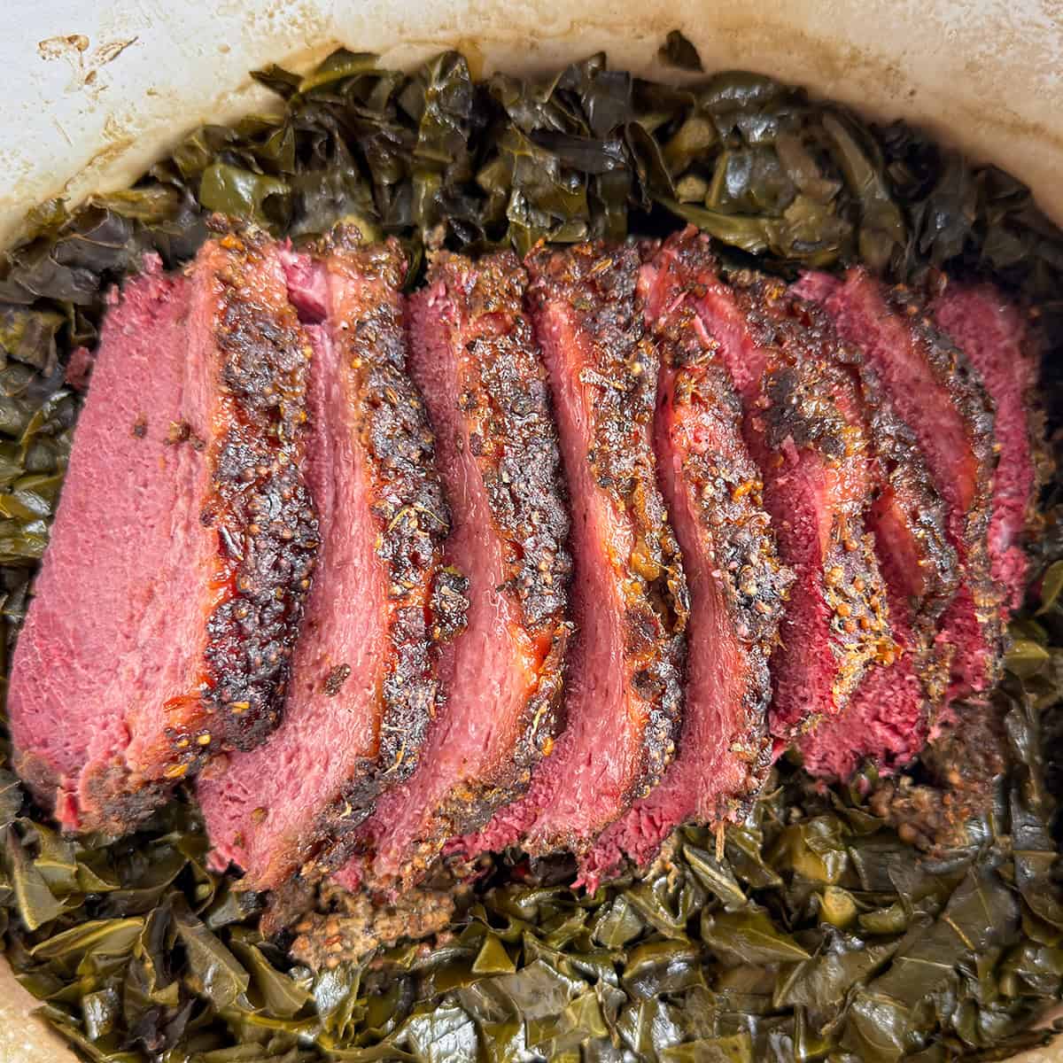 Southern style corned beef sliced over collard greens in a Dutch oven