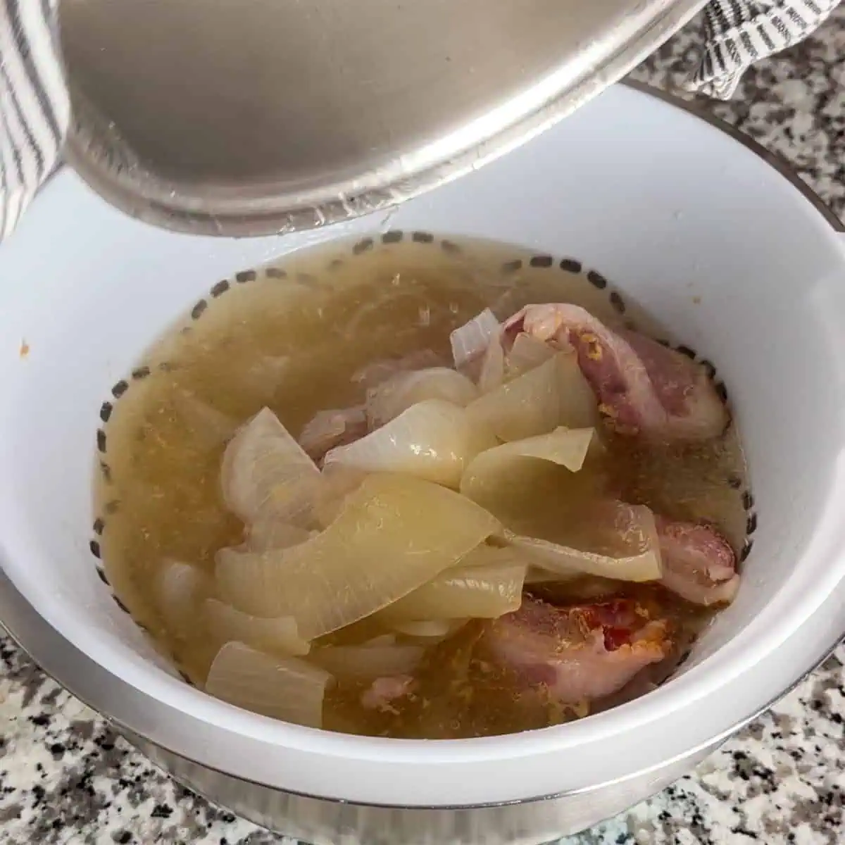 Broth being strained from cooked bacon and onions into a bowl