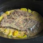 Cream of mushroom Mississippi pot roast in a slow cooker with creamy gravy and pepperoncini peppers