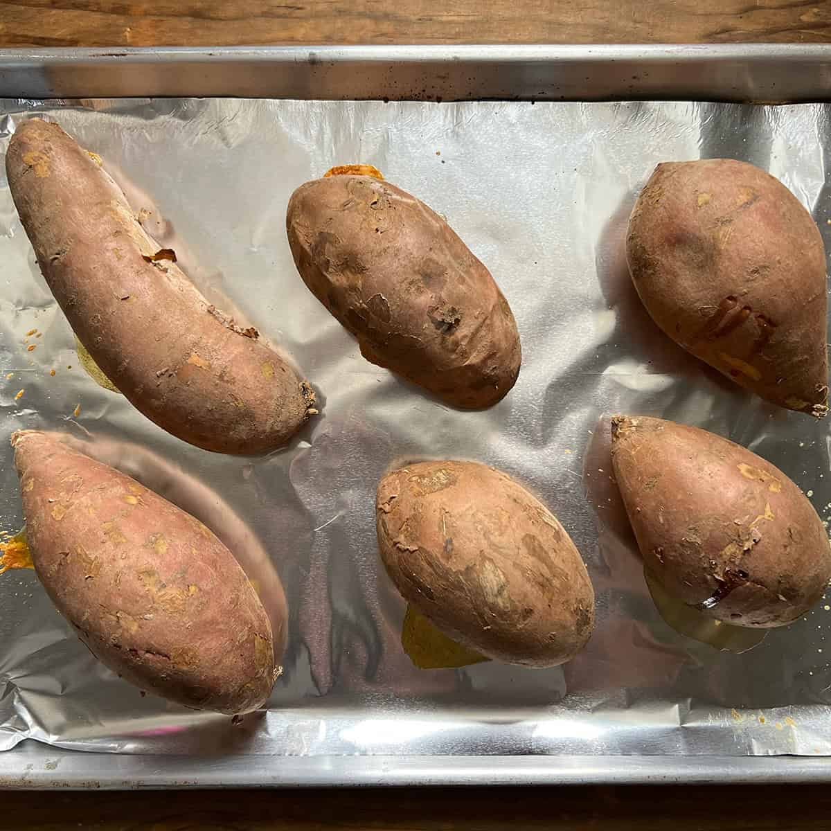 Roasted whole sweet potatoes on a foil-lined baking sheet for sweet potato pie.