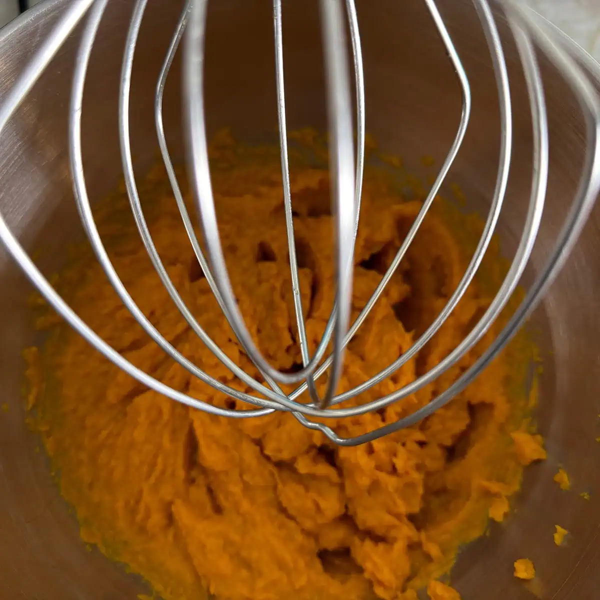 Stand mixer whisk attachment over sweet potato puree after cleaning off the strings.