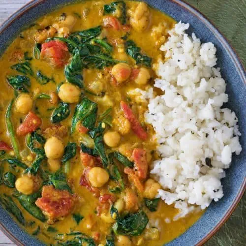 Bowl of Instant Pot chickpea curry with tomatoes, spinach, and rice.