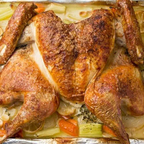 Spatchcock turkey with crispy golden skin roasted on a sheet pan with celery, carrots, lemon, and herbs