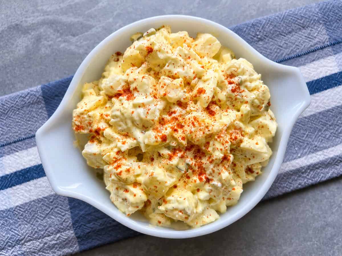 Creamy Instant Pot potato salad sprinkled with paprika in a white serving bowl