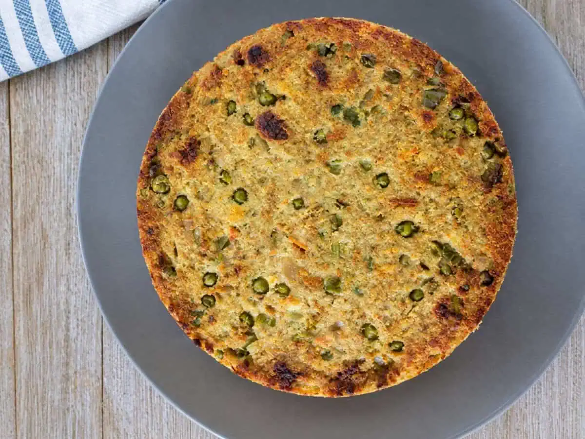 Overhead view of golden Instant Pot stuffing with peas and vegetables on a gray plate