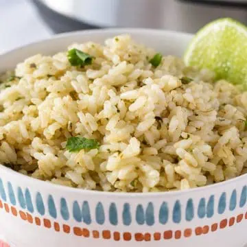 Cilantro lime rice served in a patterned bowl with fresh cilantro and a lime wedge