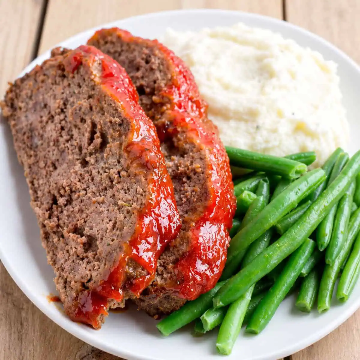 Slices of pressure cooker meatloaf with brown sugar glaze served with mashed potatoes and green beans