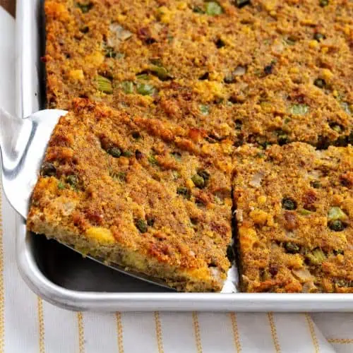 Southern cornbread dressing with browned crisp edges lifted from a sheet pan on a serving spatula